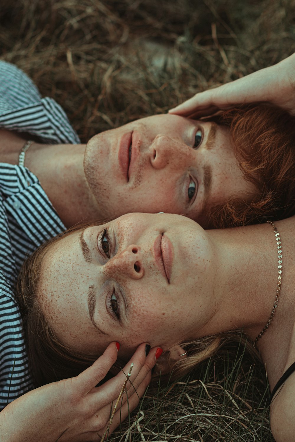 woman in white and black stripe shirt lying on brown grass