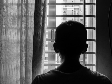 silhouette of boy standing near window