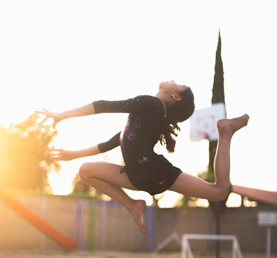 Young gymnast mid-air during a flawless artistic gymnastics routine in a bright gym.