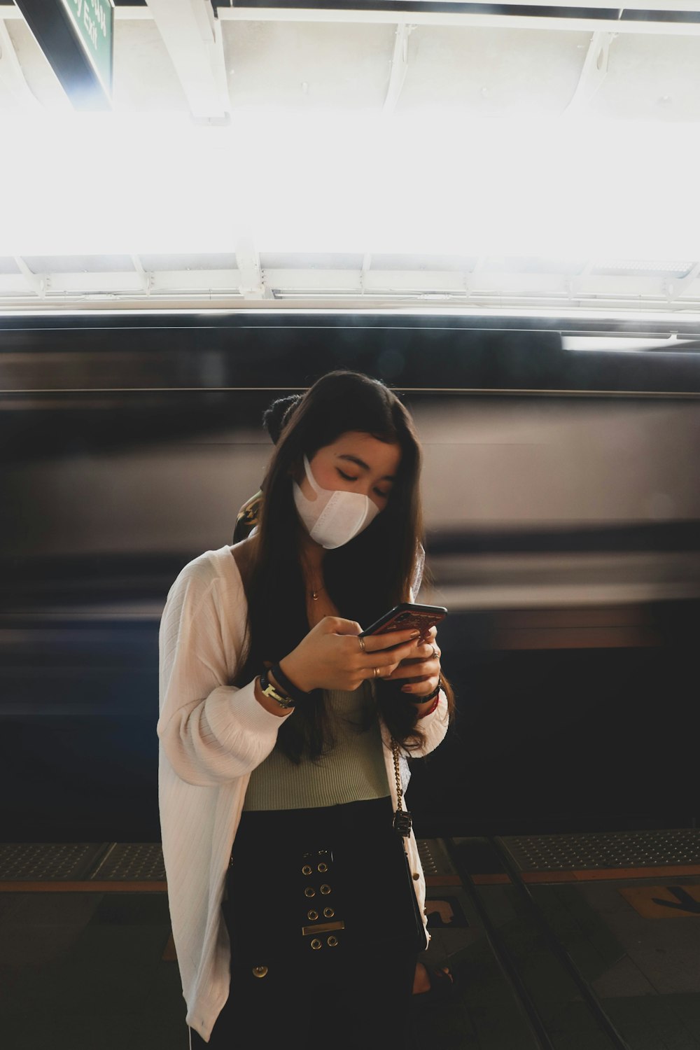 woman in white long sleeve shirt holding black smartphone