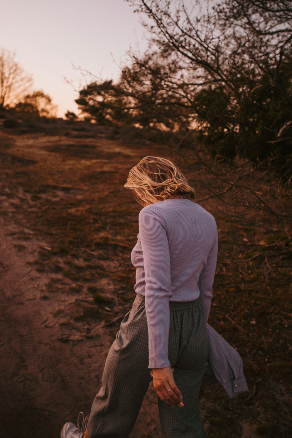 woman in gray long sleeve shirt and gray skirt sitting on brown field during daytime