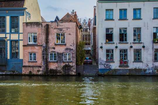 brown concrete building beside river during daytime in Gent Belgium