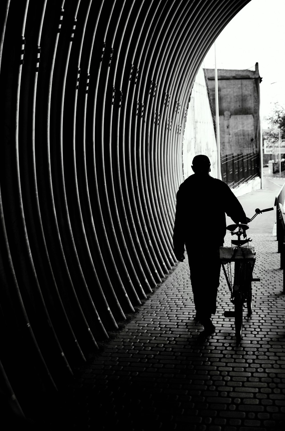 silhouette of man walking on sidewalk during daytime