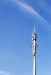 Technicians setting up communication cables on a remote tower site under a clear blue sky.
