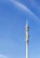 A tall communication tower with various antennas and dishes, set against a clear blue sky. The tower has multiple platforms and technical equipment attached at intervals along its height.