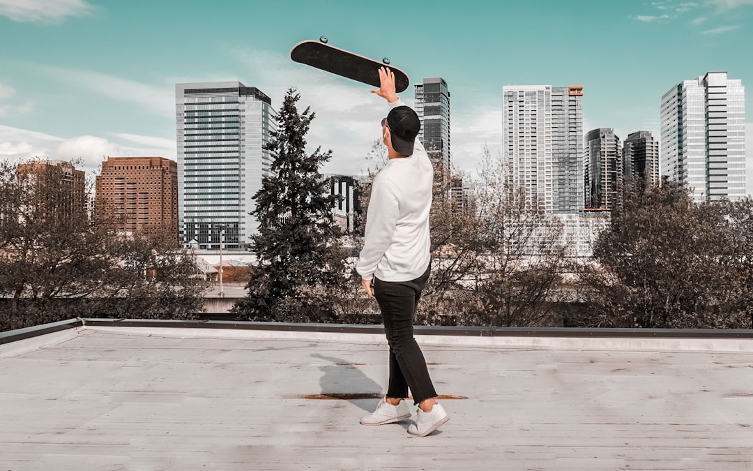 man in white hoodie and black pants standing on skateboard during daytime