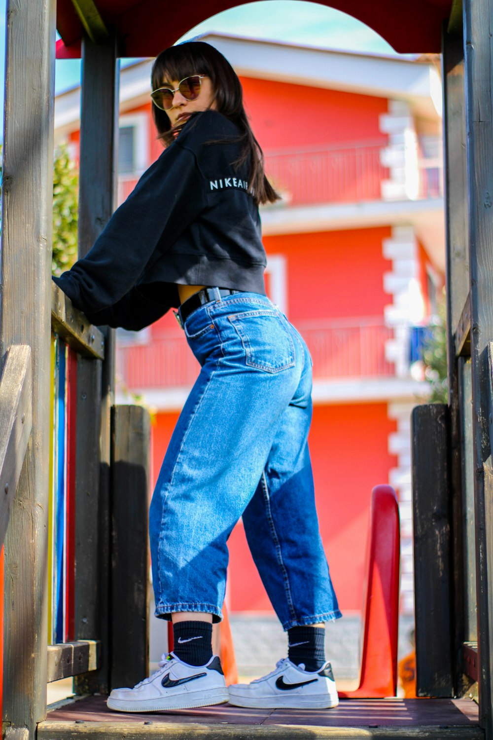 Woman in black hoodie and blue denim jeans standing beside brown wooden  post during daytime photo – Free Italia Image on Unsplash