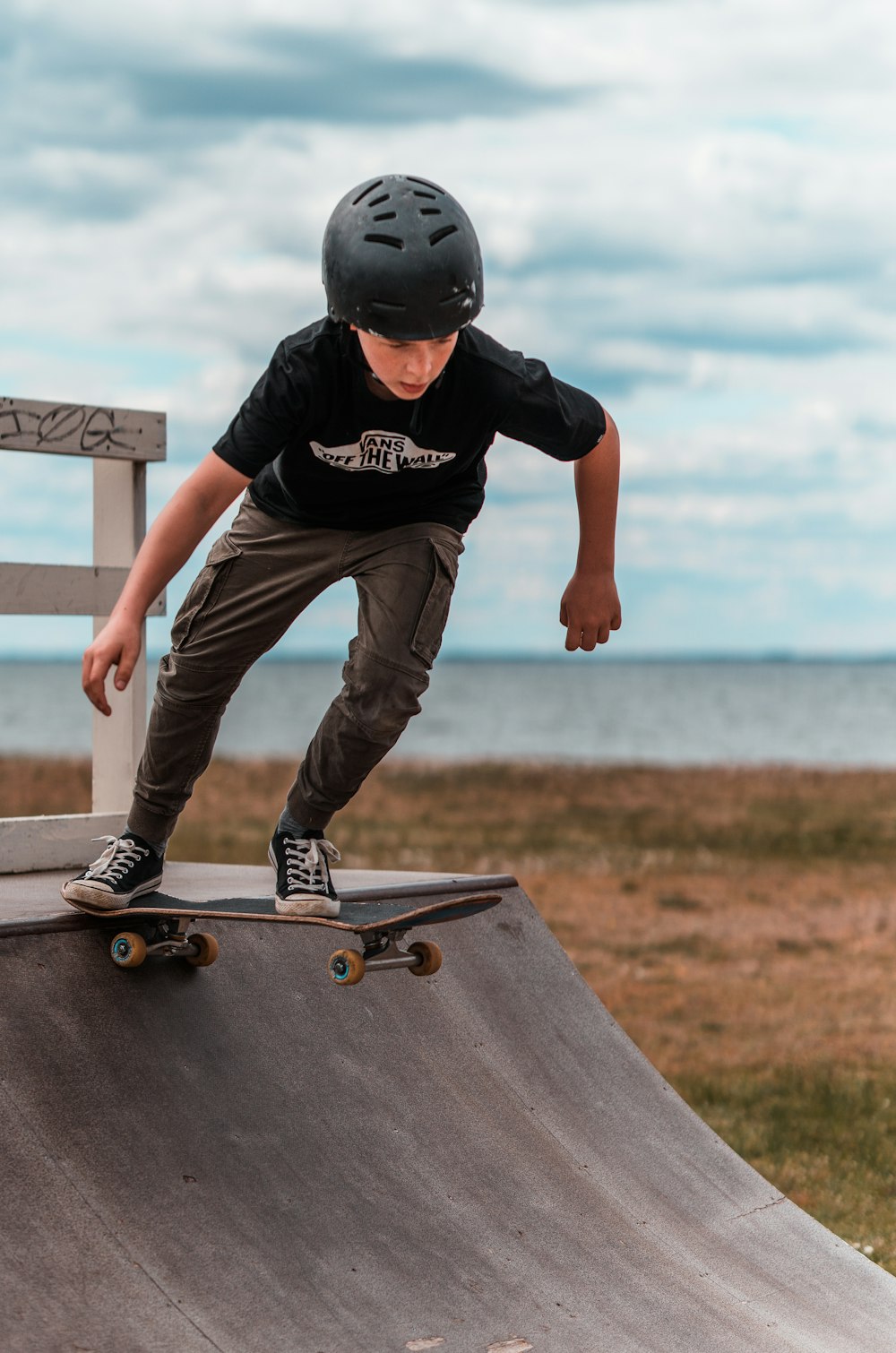 Hombre con camiseta negra y pantalones marrones con casco negro saltando sobre una mesa de madera marrón