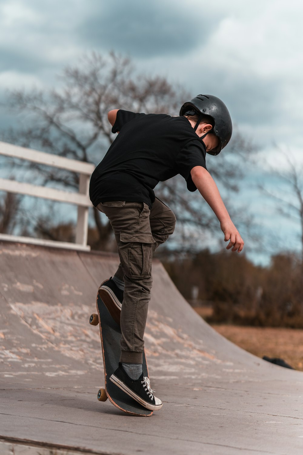 hombre con camiseta negra y pantalones marrones con gorra negra saltando en un campo marrón durante