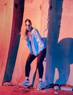 A sleek model wearing a futuristic jacket with glowing accents, captured in a dynamic urban night setting.