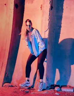 A fashion model striking a bold pose against an urban backdrop, showcasing creative lighting and style.