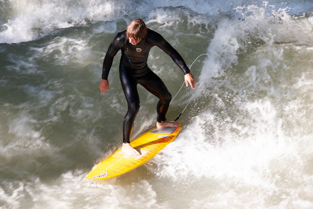 woman in black wetsuit surfing on sea waves during daytime