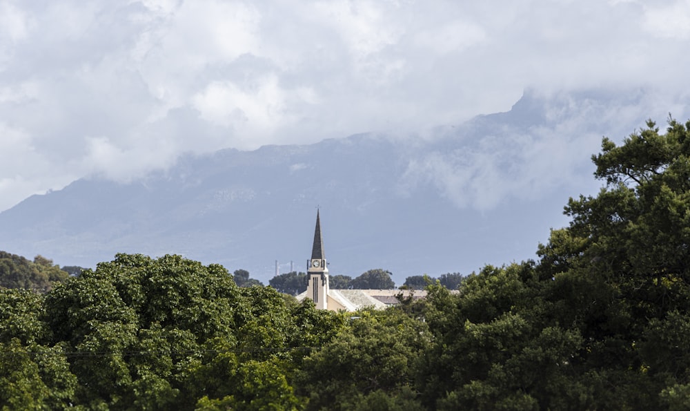 white and brown concrete building surrounded by green trees under white clouds during daytime