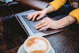 person using macbook pro on brown wooden table
