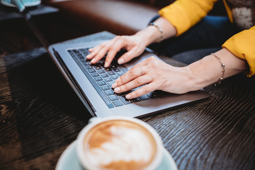 person using macbook pro on brown wooden table