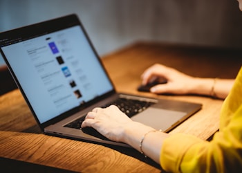 person using macbook pro on brown wooden table