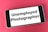 A smartphone lies on a red surface, displaying the text 'Unemployed Photographer' on its screen.