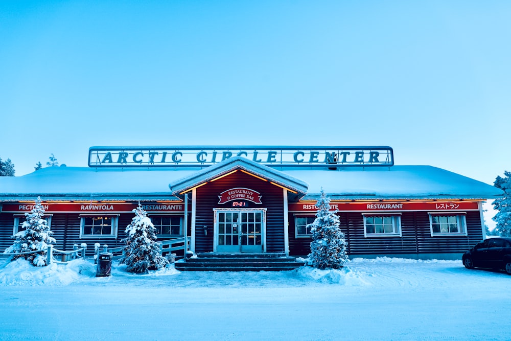 Casa de madera roja y blanca con árboles cubiertos de nieve durante el día