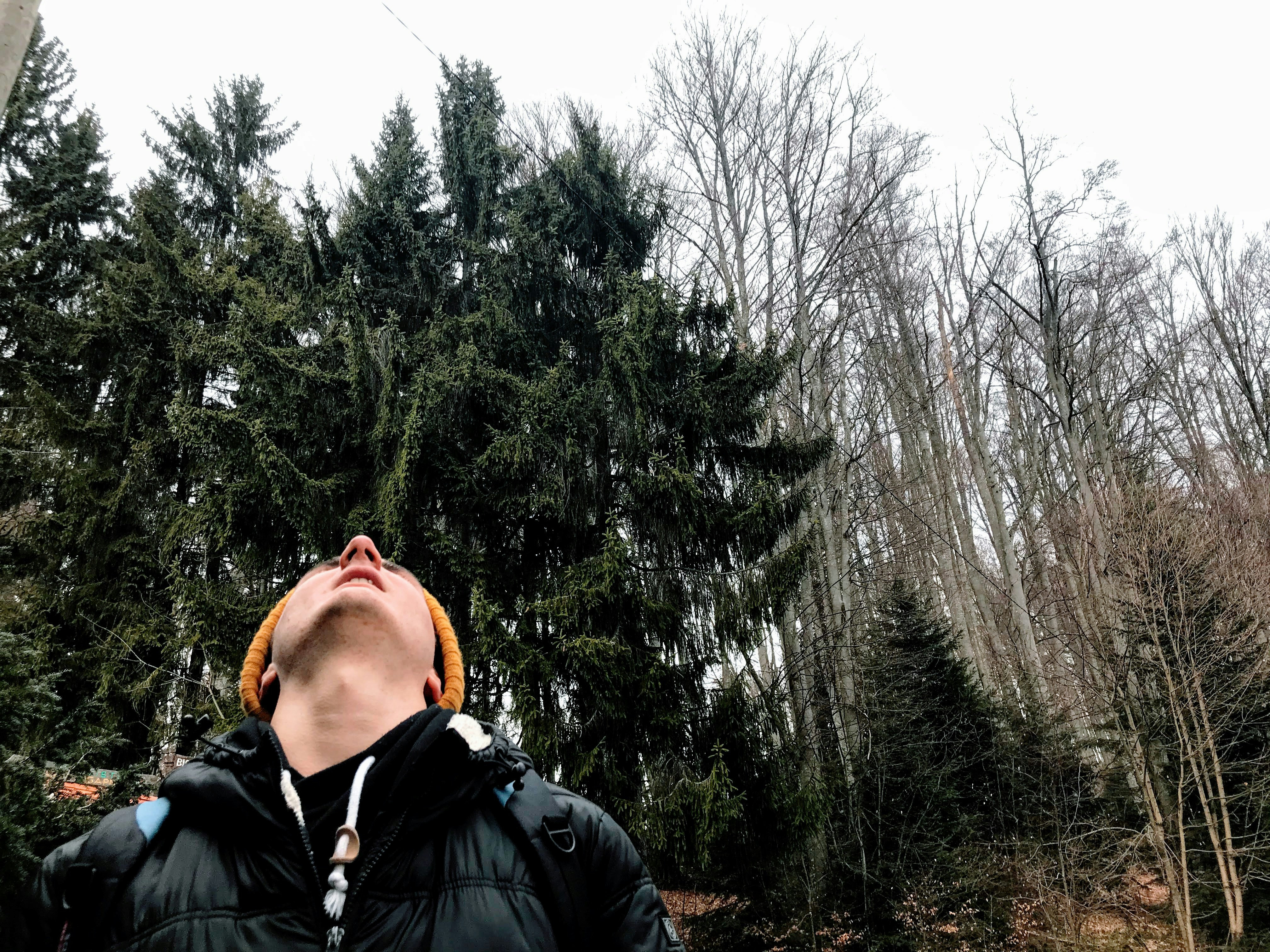 man in black jacket standing near green trees during daytime