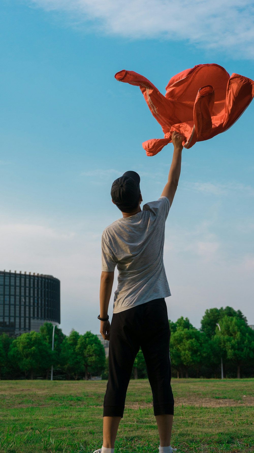 man in white t-shirt and black pants holding orange textile during daytime