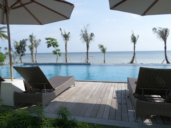 Close-up of a wooden deck with sun loungers beside a clear blue private pool.