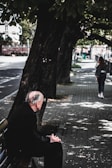 An elderly man sitting on a park bench, reflecting.