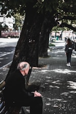 An elderly man sitting on a park bench, gazing thoughtfully into the distance.