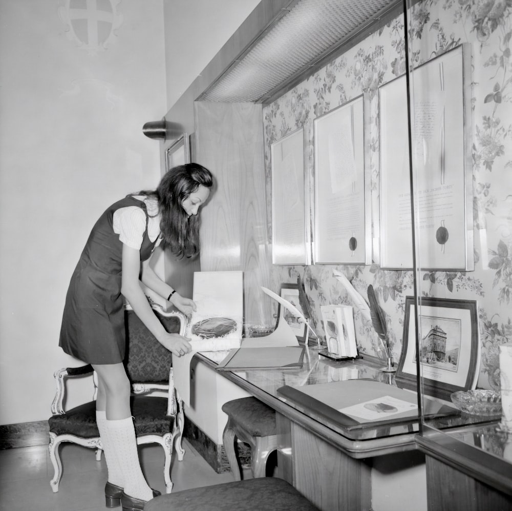 woman in white t-shirt and black pants standing beside table