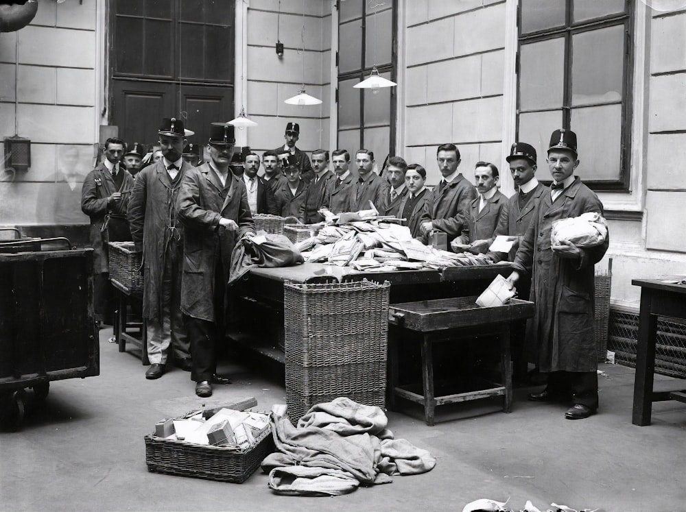 grayscale photo of people standing near table