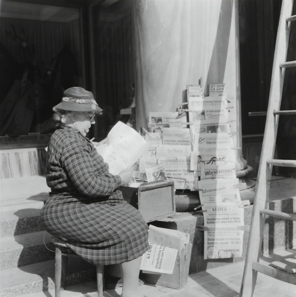 man in plaid shirt sitting on chair reading newspaper