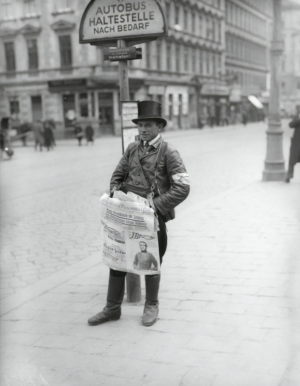 grayscale photo of woman in black jacket and hat standing on sidewalk