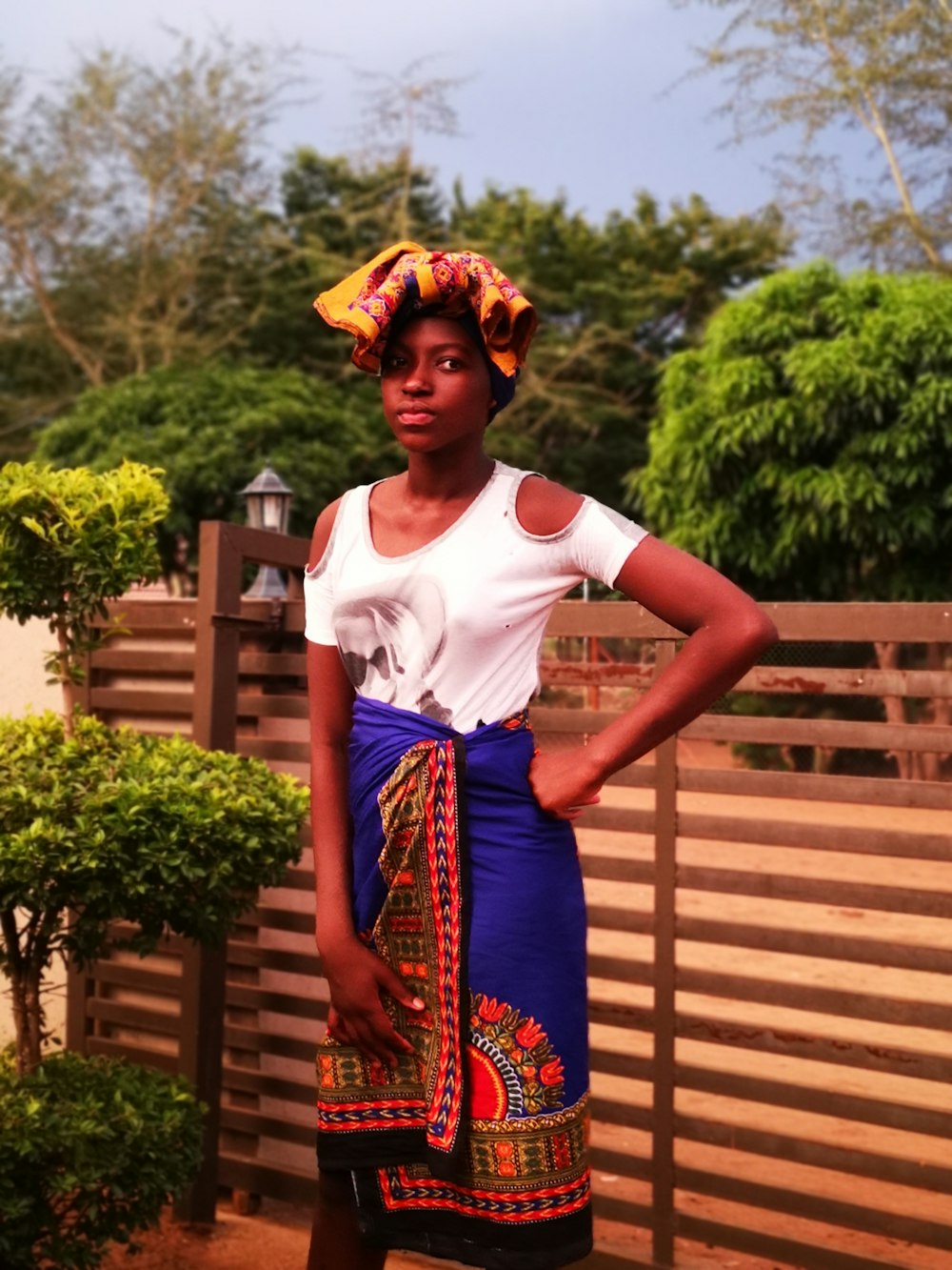 woman in white crew neck t-shirt and blue and red floral skirt standing near brown