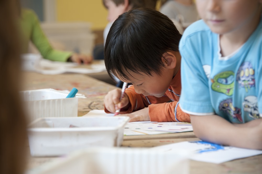 boy in blue t-shirt writing on white paper