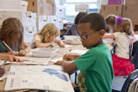 boy in green sweater writing on white paper
