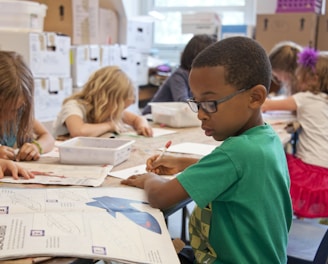 boy in green sweater writing on white paper