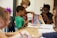 A group of children engaged in a lively discussion around a table filled with books.