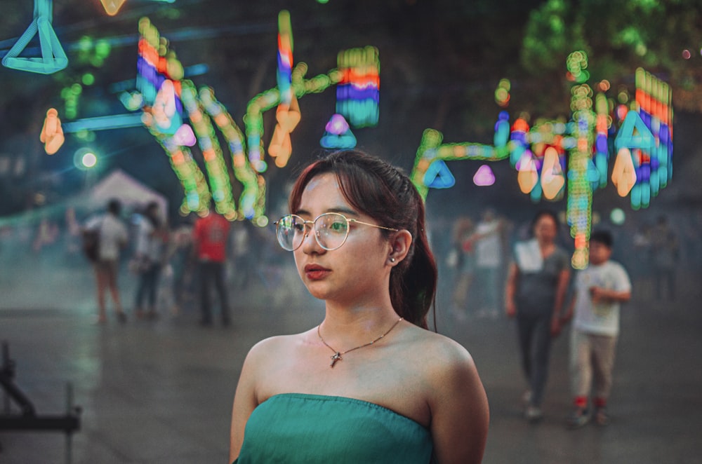 woman in teal tube dress wearing eyeglasses