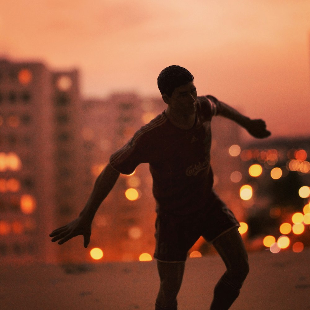 homme en chemise noire et short courant sur le terrain au coucher du soleil