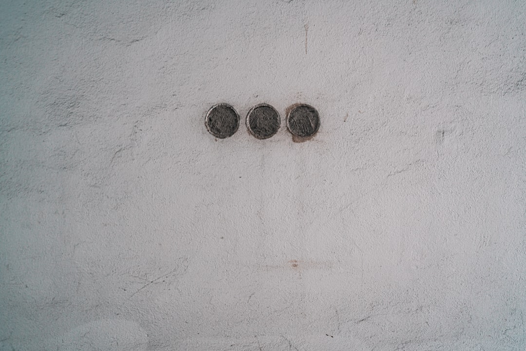 four round silver coins on white concrete wall