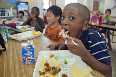 Children smiling happily while eating balanced meals at a Nutrisinusa program.