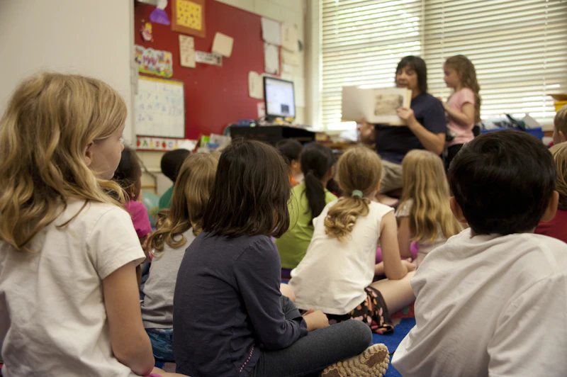A friendly teacher reading a picture book to a group of children