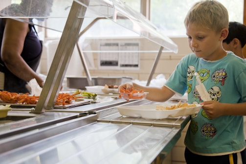 Children happily picking up their pre-ordered meals at a canteen counter.