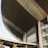 A modern architectural structure with a large, curved roof and glass windows. The building is prominently labeled 'Dewan Agung Tunku Canselor'. The facade showcases geometric shapes and a combination of concrete and glass elements, conveying an innovative design.