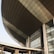 A modern architectural structure with a large, curved roof and glass windows. The building is prominently labeled 'Dewan Agung Tunku Canselor'. The facade showcases geometric shapes and a combination of concrete and glass elements, conveying an innovative design.