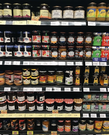 Small jars of homemade jam and spreads lined up on a wooden shelf in the bakery