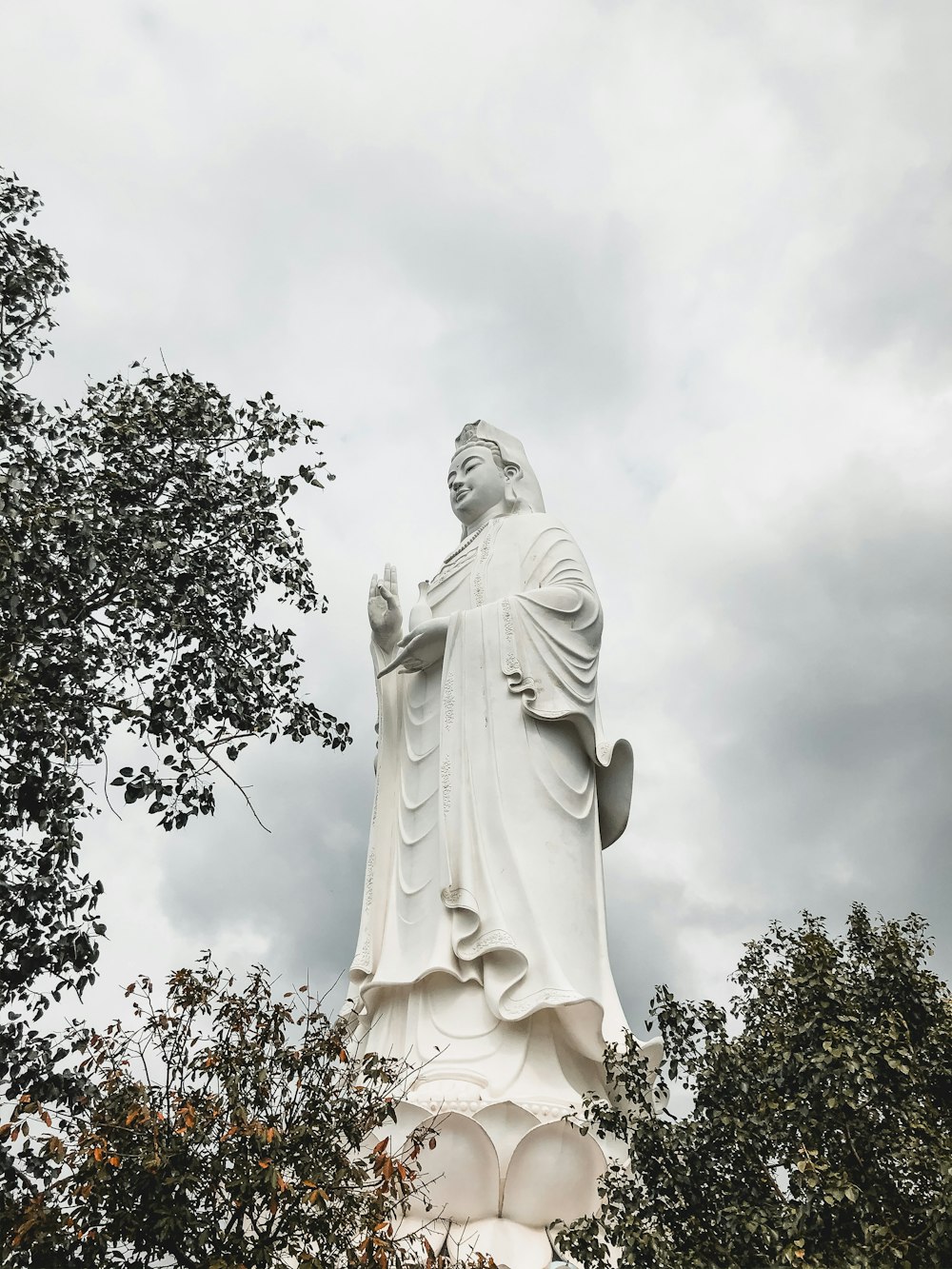 white angel statue near green tree during daytime