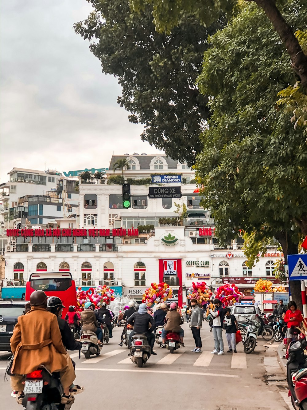 people in a street with cars parked in front of a building