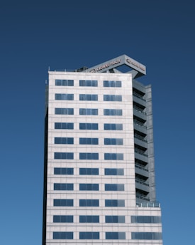 A high-rise building with a modern design set against a clear blue sky. The structure features a grid pattern of windows and a sign on top displaying 'Crowne Plaza.'