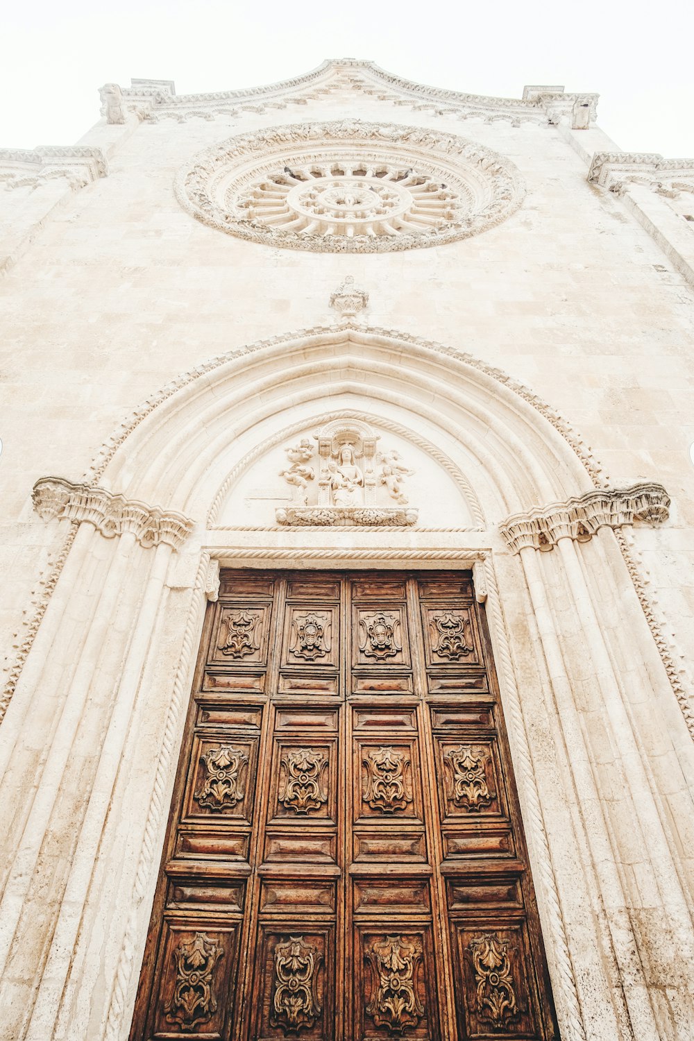 Porta di legno marrone su edificio in cemento bianco