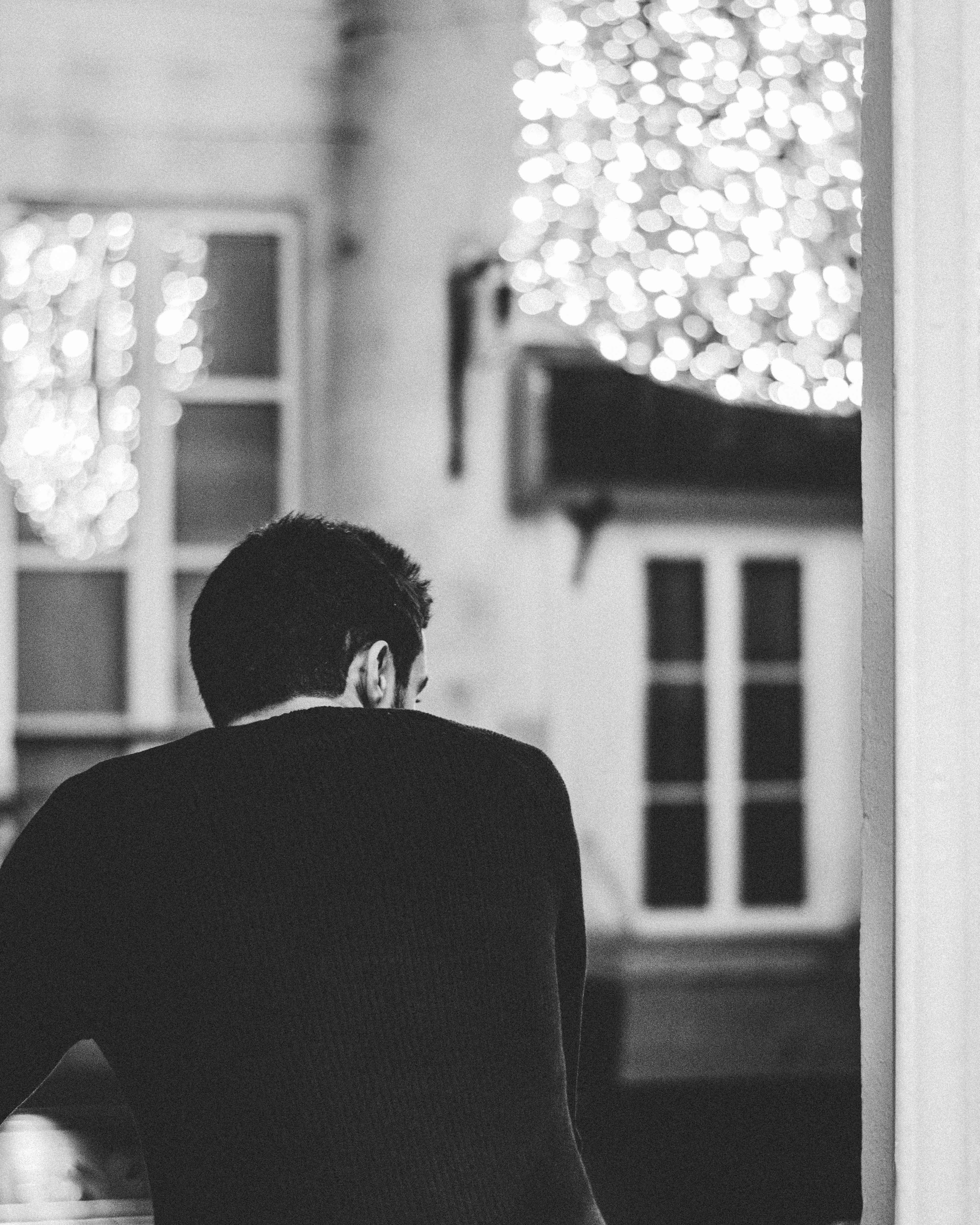 man in black suit standing in front of window